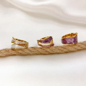 Close-up of three adjustable 18K gold-plated enamel rings on rustic rope and white silk
