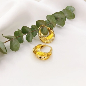 Irregular twisted gold earrings with vintage hammered texture on white silk background