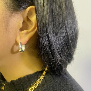 Close-up of minimalist silver geometric chunky hoop earrings worn on a female model
