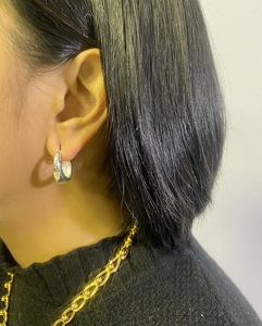 Close-up of polished silver teardrop earrings and a gold beaded necklace on a model
