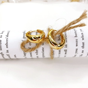 Macro shot of 18K gold plated thick hoop earrings on white decorative paper rolls