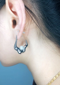 Close-up of irregular silver-tone earring with a white pearl on a female model