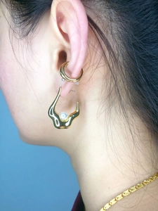 Detail of 18K gold plated drop earrings with pearl inlay and modern minimalist curved design