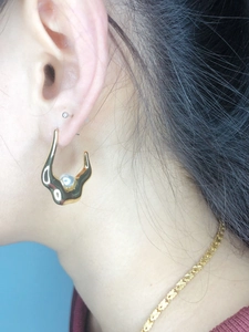 Detail of 18K gold-plated lava ear stud featuring a white pearl on a fashion model