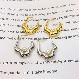 Detail of 18K gold plated and silver abstract pearl earrings on a text backdrop