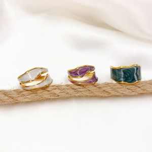 Detailed view of wavy 18K gold plated rings with white, purple and green enamel inlay