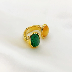 Detail of adjustable gold ring with oval green malachite and orange gemstone settings