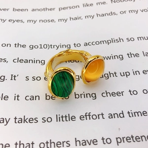 Detailed close-up of a vintage gold open ring featuring green and amber gemstones