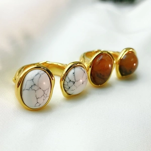 Macro shot of 18K gold plated rings with marble and carnelian stones on white silk