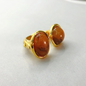 Detail of an adjustable gold ring featuring two oval amber stones in a vintage style