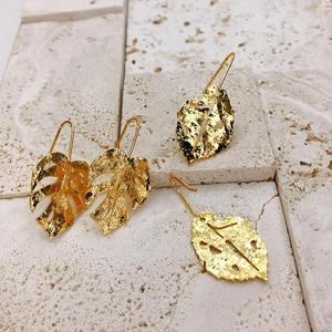 Macro detail of 18K gold plated monstera leaf earrings with hammered metal texture