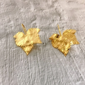 Close-up of golden leaf earrings with a hammered texture and 18K gold-plated finish