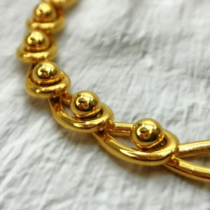 Makroaufnahme des 18K vergoldeten Armbands mit industriellen Gliedern und Kugelknoten