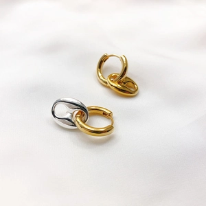 Dettaglio macro di orecchini a naso di maiale in oro 18K e argento su seta bianca