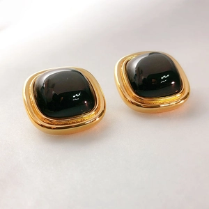 Detail of 18K gold plated square clip-on earrings with dark gemstone inlay and vintage design