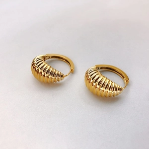 Détail de créoles dorées à l'or 18 carats avec un design torsadé style croissant