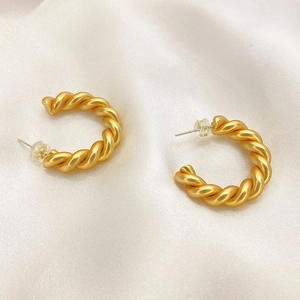 Élégantes créoles torsadées plaquées or 18K avec fini mat sur du satin blanc luxueux