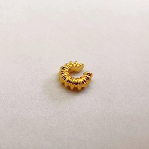 Detailaufnahme einer vergoldeten C-Ohrmanschette mit Spiraltextur und poliertem Finish