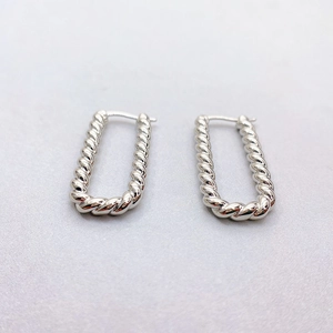 Macro detail of silver twisted rope earrings in a rectangular U-shaped metallic design
