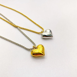 Detailed close-up of mixed gold and silver solid heart pendant necklaces with woven chains