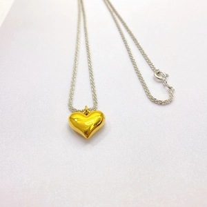 Two-tone necklace featuring a gold heart pendant and silver chain in a flat lay view