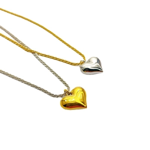 Fashionable gold and silver heart pendant necklaces with woven metal chains on white background
