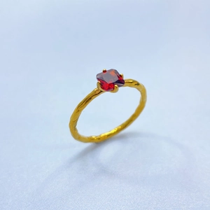 Detail of vintage 18K gold plated ring with square red gemstone and lava texture finish