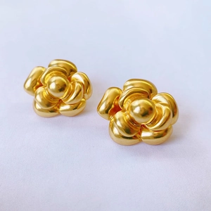 Makroaufnahme von Kamelien-Ohrsteckern in Gold mit mehrlagigen Blütenblättern und Metallglanz