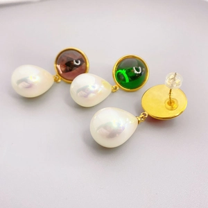 Detail showing 18K gold-plated teardrop earrings with crystals and pearl pendants