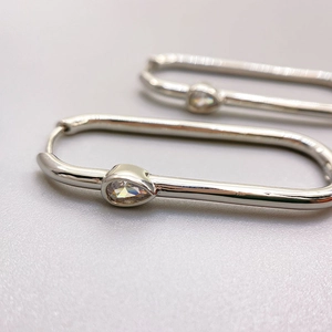 Polished silver oval hoop earrings featuring a pear-cut zircon drop in minimalist style