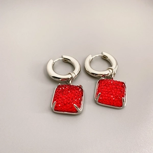 Détail de boucles d'oreilles carrées en pierre rouge avec anneaux argentés et paillettes