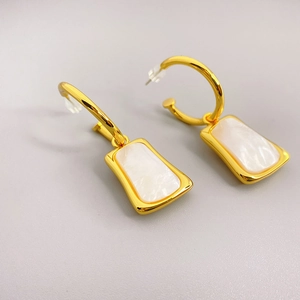 Close-up of gold-plated C-shaped earrings with inlaid white mother of pearl shells