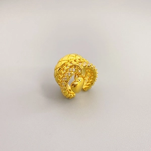 Quilted gold ring with diamond edges and a hanging heart pendant on gray background