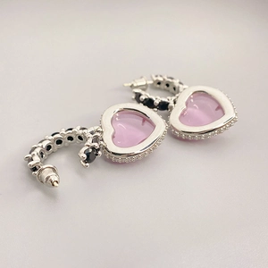 Détail de boucles d'oreilles cœur rose avec pavage de zircons noirs et blancs