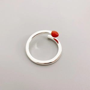 Detail of creative matchstick ring featuring vibrant red enamel tip and silver metal finish