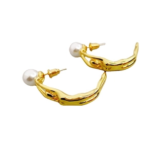 Boucles d'oreilles baskets dorées artistiques avec accents de perles sur fond blanc