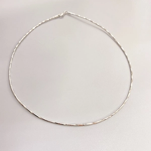 Collier minimaliste simple plaqué or blanc 18K en laiton pour femme sur fond gris neutre