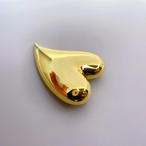 Polished 18K gold heart-shaped brass brooch with high gloss finish on purple background