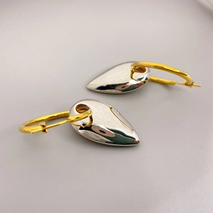 Modern mixed metal hoop earrings with gold circle and silver heart teardrop pendant