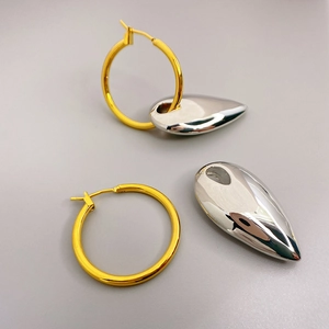 Fashionable gold hoop earrings featuring a silver teardrop charm with a polished finish