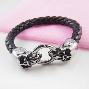 Macro shot of punk skull charms on black braided leather bracelet for men