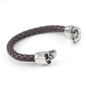 Close-up of woven dark brown leather cord with aged silver skull charms and metal clasp