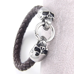 Close-up of punk braided leather bracelet featuring detailed silver skull metal charms