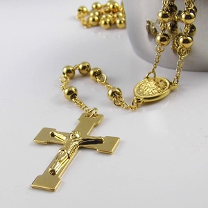Détail macro du chapelet en acier inoxydable plaqué or 18 carats avec pendentif croix