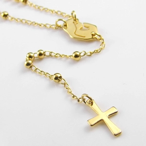 Detail view of a gold rosary cross necklace with polished beads on a white background