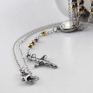 Close-up of a triple-layered cross and medal necklace with tricolor metallic beads