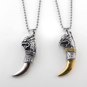 Detail of silver and gold stainless steel wolf tooth pendants with intricate carved textures