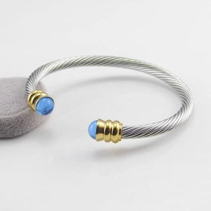 Detail of twisted cable stainless steel bracelet with golden rings and blue resin stones