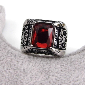 Macro detail of men's vintage steel ring with faceted red gemstone and black enamel