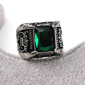 Detailed view of emerald-cut green stone ring with ornate silver floral engravings